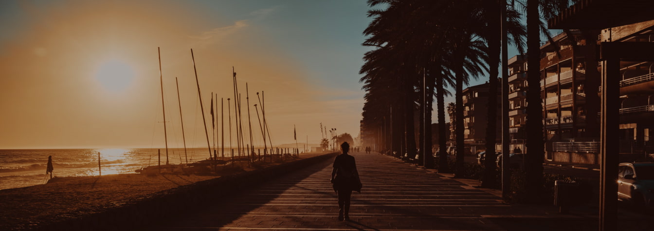 Persona paseando por el Paseo Marítimo de Calafell durante la puesta de sol