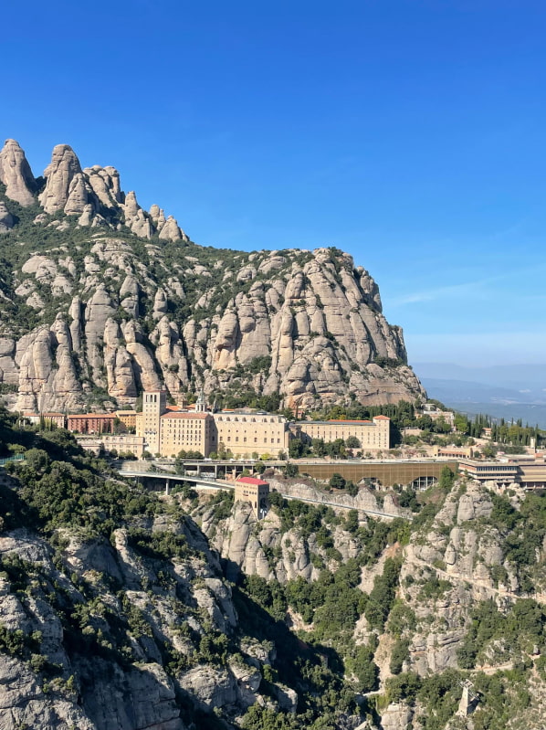 Monasterio de Montserrat visto de lejos, enclavao entre sus características montañas.