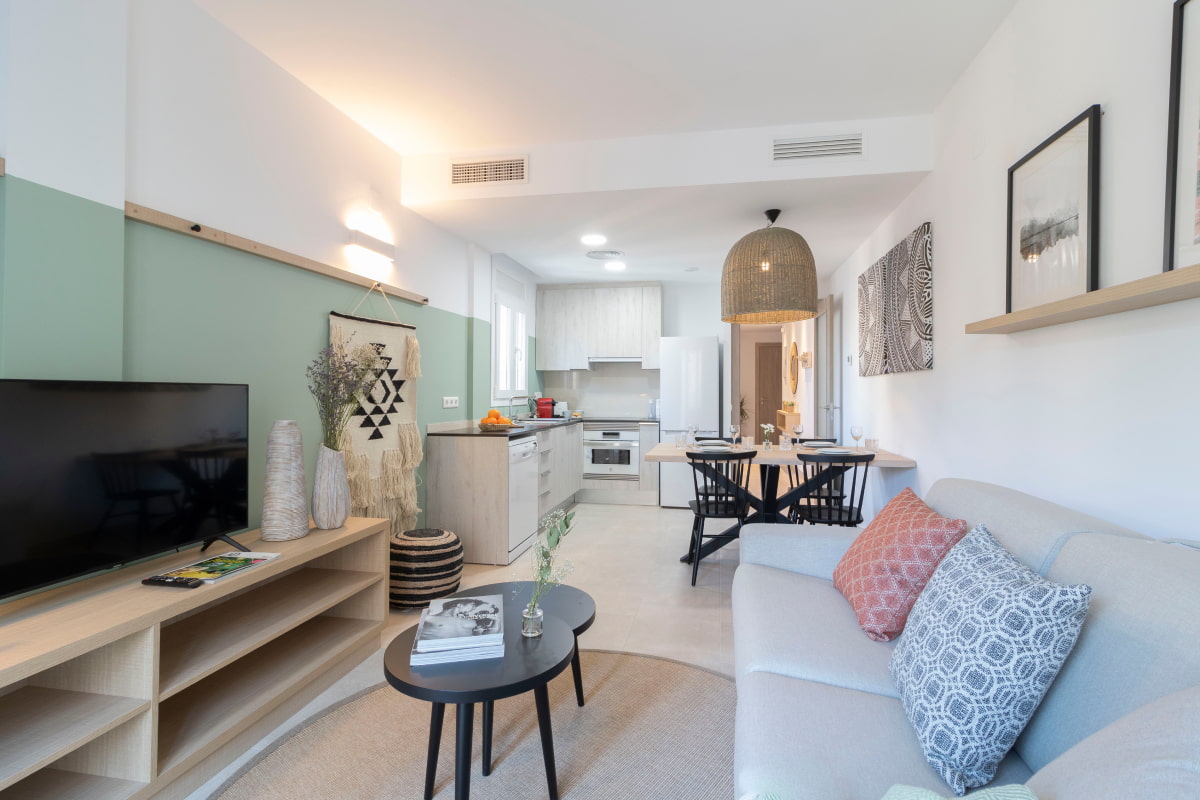 Cosy living room with a sofa, flat-screen TV, and an open-plan kitchen.