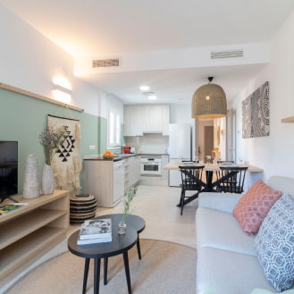 Cosy living room with a sofa, flat-screen TV, and an open-plan kitchen.