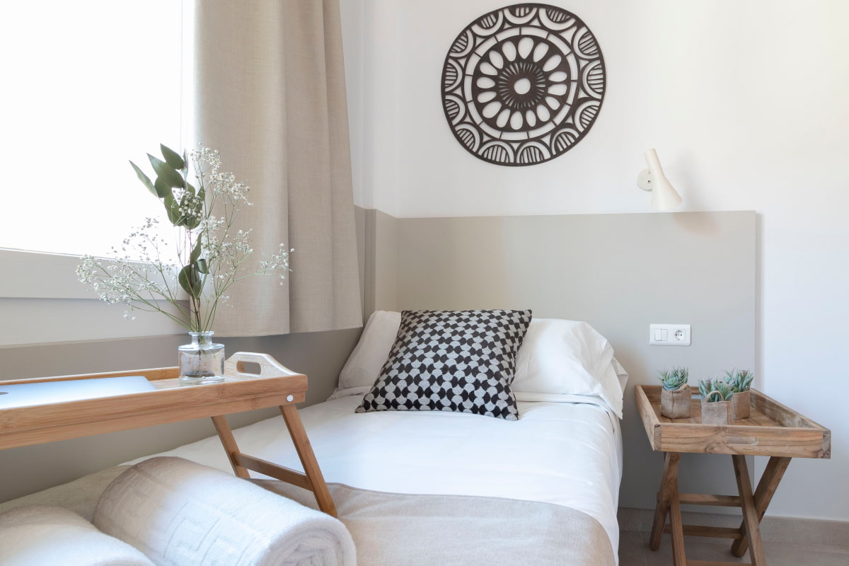 Single bed with white sheets and a pillow, in a room decorated with ethnic motifs.