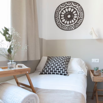 Single bed with white sheets and a pillow, in a room decorated with ethnic motifs.