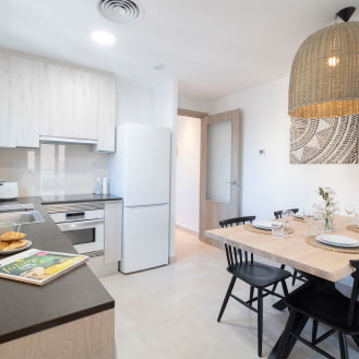 Kitchen in one of the apartments at Calafell Home Apartments, featuring a fridge, oven, and wicker lamp.