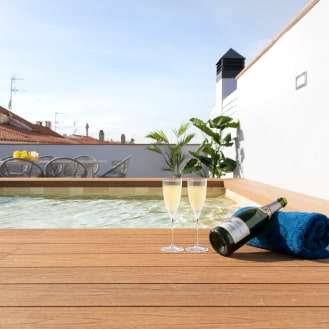 Bottle of champagne and a towel on the wooden decking surrounding the jacuzzi pool at Calafell Home Apartments.