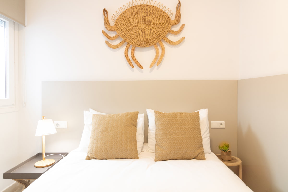 Double bedroom combining white tones with sandy colours and raffia details.