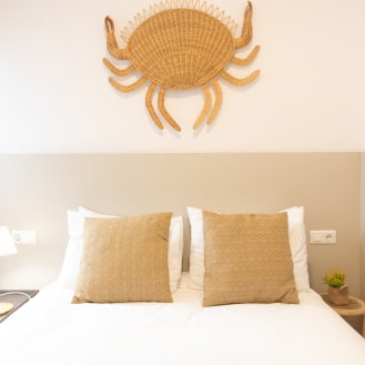 Double bedroom combining white tones with sandy colours and raffia details.