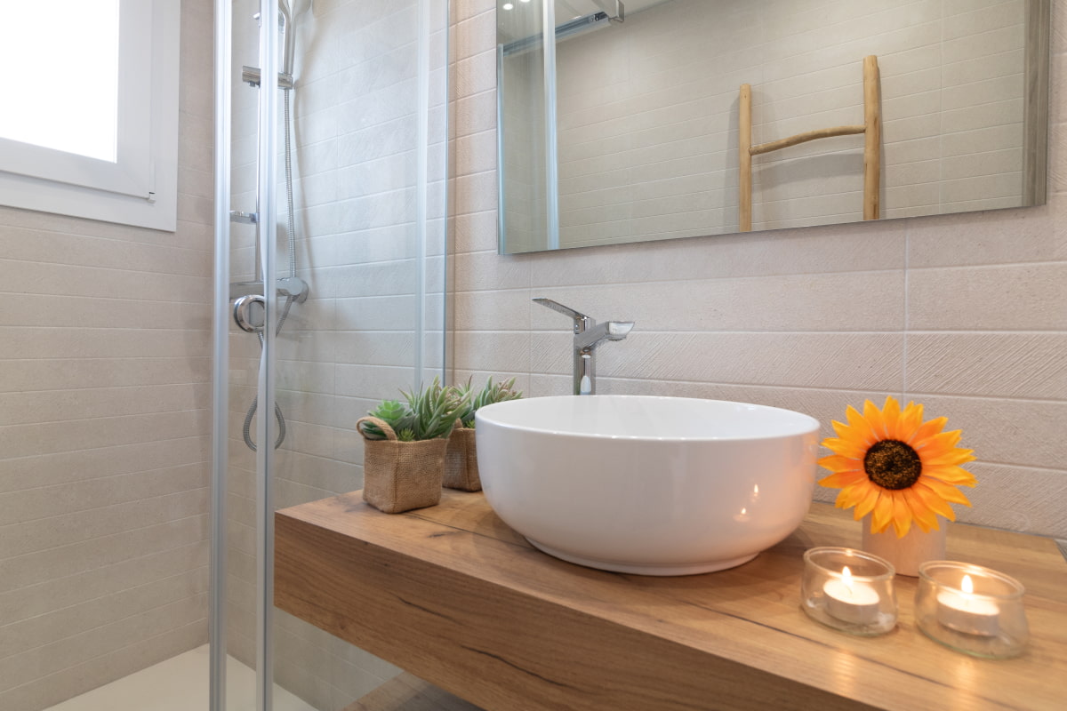 Modern countertop washbasin with lit candles and floral details.