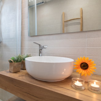 Modern countertop washbasin with lit candles and floral details.