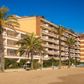 Promenade along Calafell Beach, flanked by buildings and palm trees.