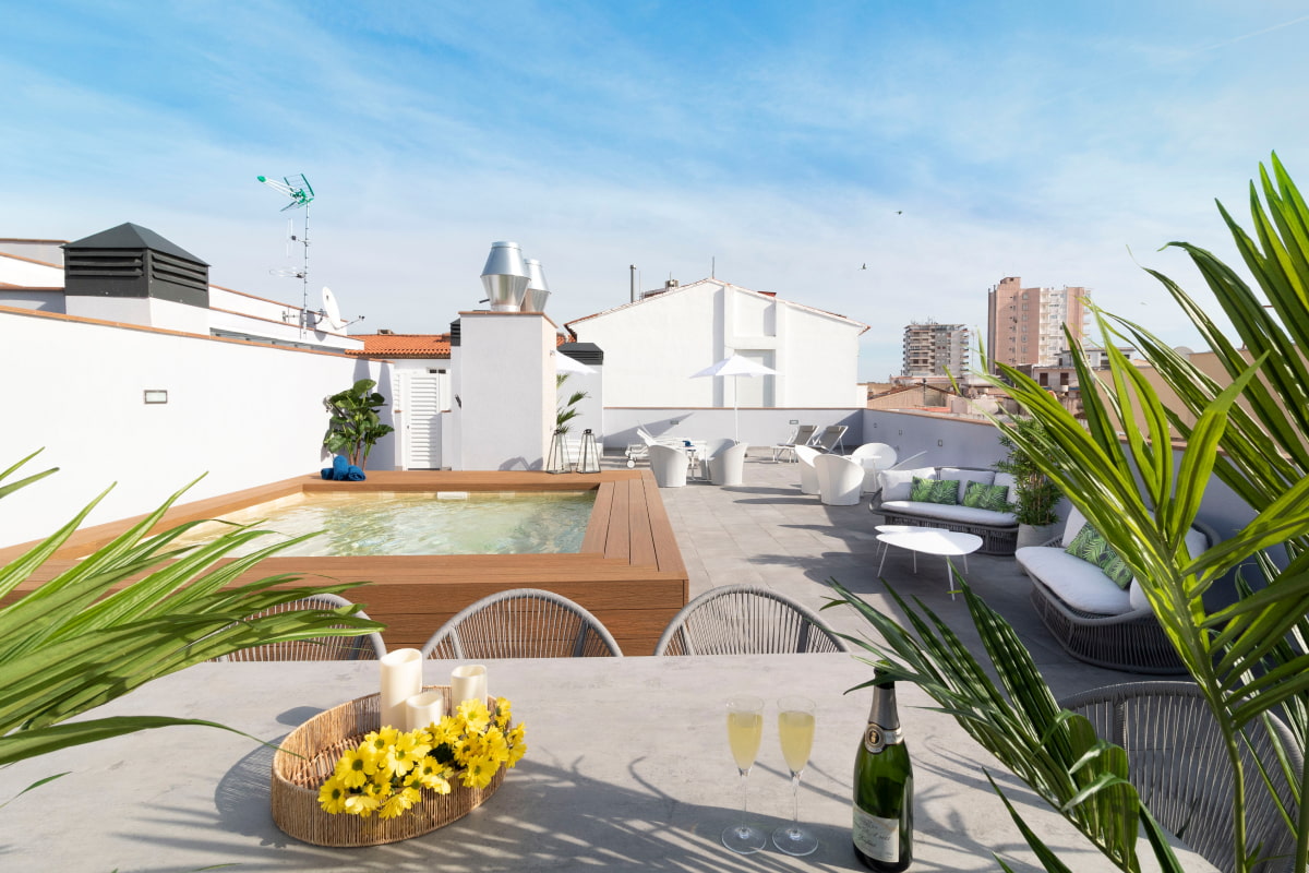 General view of the rooftop at Calafell Home Apartments: tables and chairs, jacuzzi pool, and chill-out area.