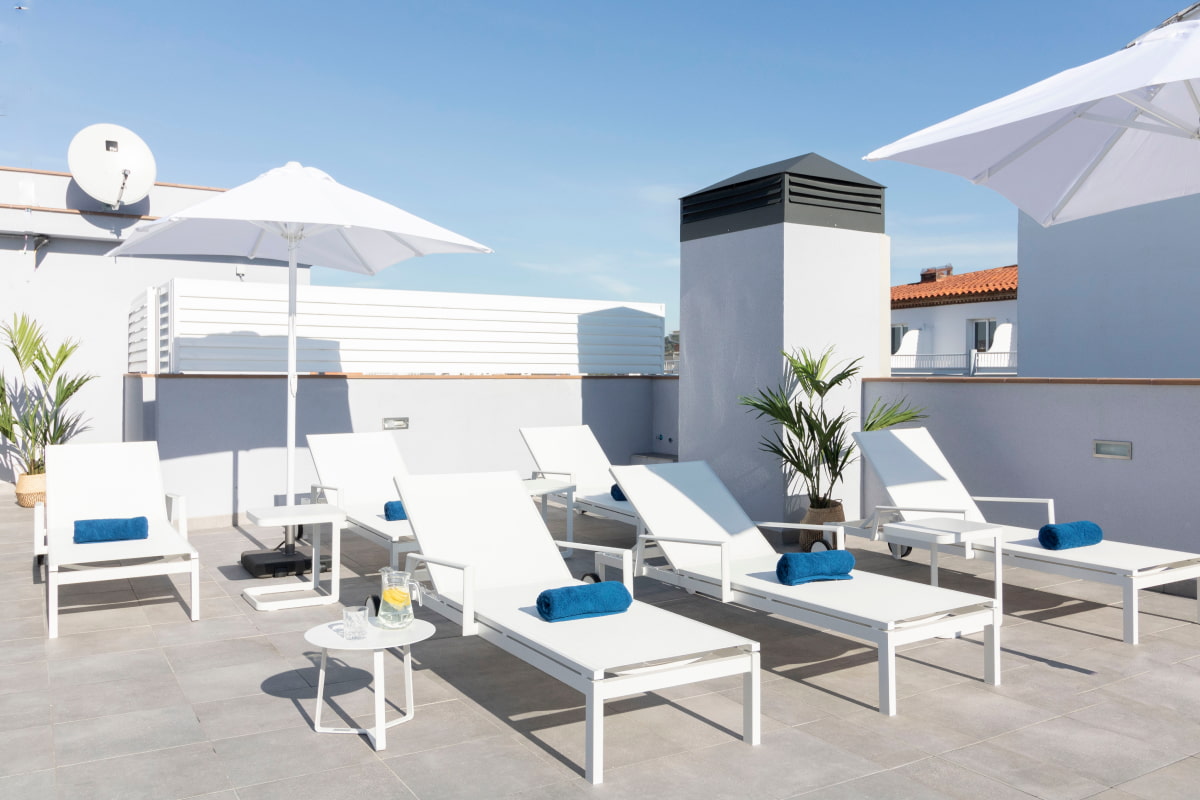 Outdoor rooftop space with white umbrellas and deck chairs, ideal for moments of tranquillity.