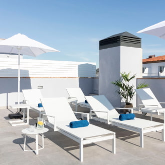 Outdoor rooftop space with white umbrellas and deck chairs, ideal for moments of tranquillity.