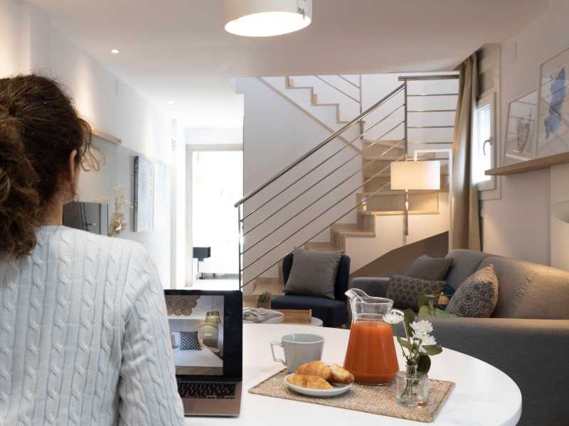 Huesped de uno de los apartamentos desayunando en el salón mientras consulta un PC